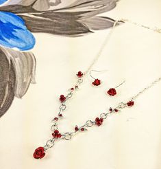 "Red carved metal rose necklace and matching earrings.  The small carved metal roses are set onto the silver plated branches and are accented with red crystals.  Each rose is metal and red enamel is applied to them.   It makes a nice delicate floral accent piece with any outfit. Each rose is approximately .19 to .25 inches. Necklace length is approximately 16.5 inches with a 2\" extender  Pierced Earrings are .75 inches long" Rose Colored Dangle Jewelry With Rose Design, Metal Rose Design Jewelry For Wedding, Wedding Jewelry With Rose Design In Metal, Silver Metal Jewelry With Rose Design, Elegant Rose Red Jewelry With Rose Design, Metal Rose Design Jewelry For Valentine's Day, Valentine's Day Metal Jewelry With Rose Design, Rose Sterling Silver Jewelry For Valentine's Day, Valentine's Day Sterling Silver Rose Jewelry