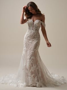 a woman in a wedding dress posing for the camera with her hand on her head