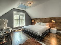 a bedroom with a bed, dresser and window in the attic style room that has wood floors