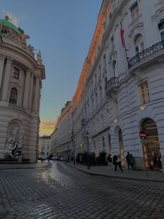 people are walking on the cobblestone street in an old european city at sunset