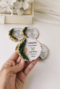 someone is holding up some cookies with the names of their wedding guests on them in front of white flowers