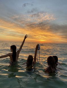 three people in the water with their arms up