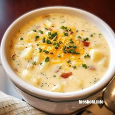 a white bowl filled with soup and cheese on top of a table next to a spoon