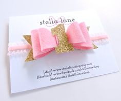 a pink and gold hair bow on a white card with the words stella lane written below it