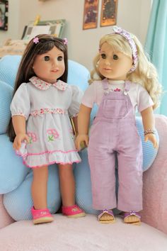 two dolls are sitting on a chair in the living room, one is wearing overalls and the other has pink shoes