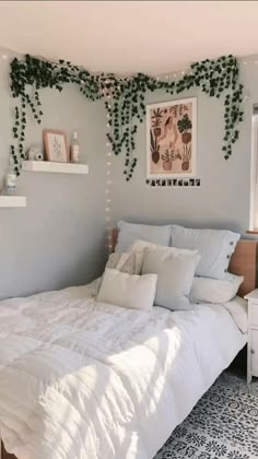 a bed with white sheets and pillows in a room decorated with plants on the wall