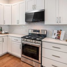 a kitchen with white cabinets and stainless steel stove top oven in the center of the room