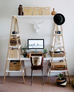 a desk with two shelves and a computer on it, in front of a cow skull mounted to the wall