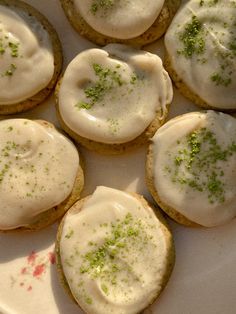 several cookies with white frosting and green sprinkles on them sitting on a plate