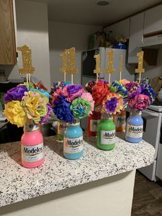 four jars with flowers in them sitting on a counter