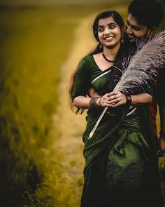 a woman in a green sari hugging a man who is holding a large feather