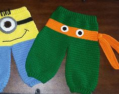 two crocheted pants with eyes on them sitting next to each other in front of a wooden table