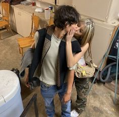 a man and woman standing next to each other in a room filled with chairs, trash cans and furniture