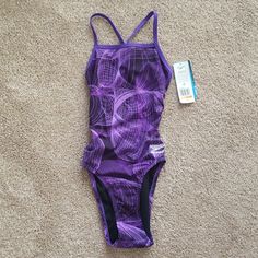 a purple swimsuit laying on the floor next to a tag