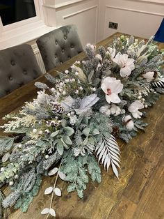 a wooden table topped with flowers and greenery