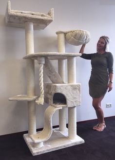 a woman standing next to a cat tree