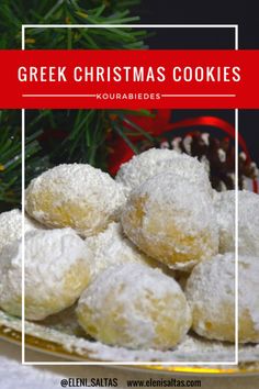 a plate filled with powdered sugar covered cookies on top of a table next to a christmas tree