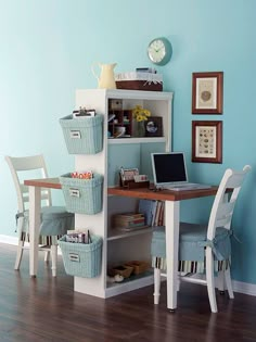 a room with a desk, chair and computer on it in front of a blue wall