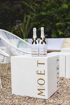 two bottles of molot champagne sitting on top of a white box