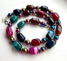 Rich jewel colours, magenta, teal, dark green, brown in these glossy agate beads, with rainbow hematite beads and discs for a luxury look. The hematite beads have a wonderful lustre. Fastened with a sterling silver clasp. The perfect statement necklace to add colour and sophistication! Agate is calming and grounding and hematite is strengthening  Length 22inches 57cms Comes boxed and gift wrapped Jewel Colours, Rainbow Hematite, Jewel Colors, Hematite Beads, Agate Beads, Green Brown, Sterling Silber, Dark Green, Necklace Etsy