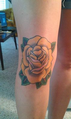 a woman's leg with a yellow rose tattoo on the lower half of her leg