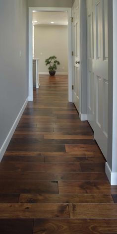 an empty hallway with white doors and wood flooring on either side of the door