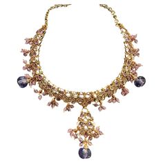 Add a touch of luxuriousness to your look with the Egyptian necklace. This ornate choker features an exquisite handmade design, delicately crafted using color to create a truly unique piece. Wear it day or night for a glamorous finish every time. Egyptian, jeweled necklace ornate with handmade tooling, beads, pear-shaped lavender, and pink-colored stones. The pendant is adjustable for length at 16" and can be reduced for a choker. The wide pattern consists of mesh that extends 2.25." long. A combination of color and beads dangle and enhance the look. Enameling and other pear-shaped stones are displayed at the top rim of the necklace. The material is a brass base with heavy 24k gold electroplating. The chain is adjustable and is 16" in length. Enameling on some bezels and scrolling. Circa 2 Ornate Purple Gemstone Jewelry, Luxury Purple Gemstone Crystal Necklace, Ornate Purple Gemstone Necklace, Luxury Victorian Amethyst Necklace, Jeweled Necklace, Egyptian Motifs, Collectible Amethyst Purple Necklace, It Day, Egyptian Necklace