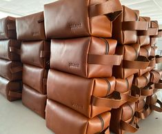 a large stack of brown leather bags sitting on top of each other in a room