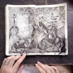 a person holding an open book with drawings on it