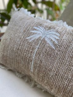 a close up of a decorative pillow on a table with plants in the back ground