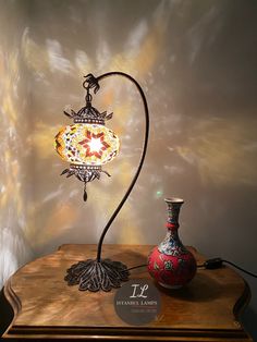 a lamp that is sitting on top of a table next to a vase with a flower in it