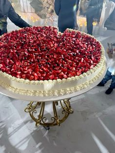 a heart shaped cake with strawberries on top is being served at a wedding reception