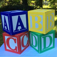 three blocks with the letters abc and c on them sitting on a table in front of some trees