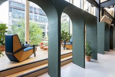 an open air lobby with blue chairs and plants