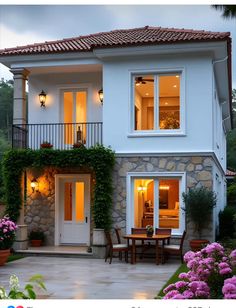 a house that has some flowers in front of it and lights on the side of the house