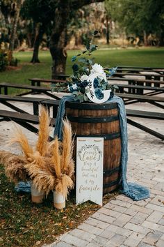 a wooden barrel with a sign and flowers on it