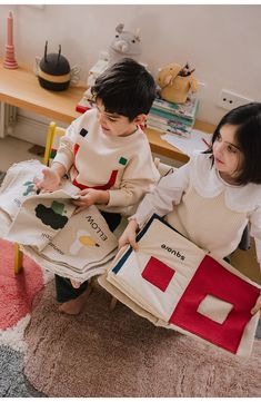 two young children sitting on the floor holding books