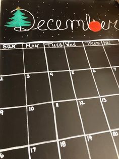 a chalkboard calendar with the word december written on it and a christmas tree drawn on it