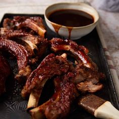 ribs on a white plate next to a cup of coffee