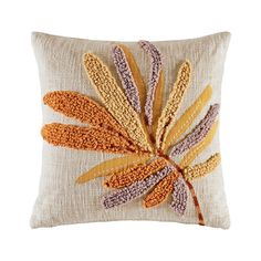 a decorative pillow with an orange and yellow flower on the front, sitting on a white surface