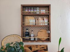 a wooden shelf with spices and other items on it next to a potted plant