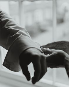 black and white photograph of two hands reaching for each other's hand in front of a window