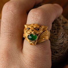 Emanate strength and elegance with this meticulously crafted jaguar ring in 18K gold. The majestic jaguar, symbolizing power and grace, showcases an emerald held firmly in its jaws, bringing a flash of lush brilliance. Further enhancing the design, its piercing eyes are intricately micro-sculpted from citrine, punctuated by black tourmaline pupils, adding depth and intrigue to the gaze. Materials: 18K gold with emerald, citrine, and black tourmaline details Measurements: Approximately 15mm tall Mens Gold Signet Rings, Golden Jaguar, Wearing Rings, Mens Emerald Rings, Mens Diamond Ring, Stone Rings For Men, Stone Ring Design, Mens Ring Designs, Man Jewelry