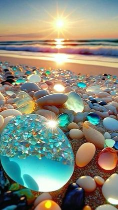 the sun is setting over some rocks on the beach with water and sand in it