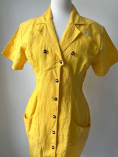 80s yellow summer statement dress black buttons with gold accents One breast pocket and two hip pockets excellent condition but there is a run in the fabric on the backside, see photos and video at the end, this is a small imperfection Designer brand is Nok Nok Shoulder pads give this dress shape 55 % Ramie 45% cotton Measurements Length 38 Chest 17.5 Waist 14.5 Sleeves 8 Measurements are taken flat Measurements: please allow a little extra room for comfortable fit and ease of movement These mea Yellow Button-up Cotton Dress, Fitted Summer Shirt Dress With Buttoned Pockets, Yellow Cotton Button-up Dress, Fitted Summer Shirt Dress With Pockets, Yellow Button-up Shirt Dress, Yellow Button-up Shirt Dress With Buttons, Collared Yellow Dress For Work, Fitted Yellow Shirt Dress For Summer, Vintage Dresses With Button Closure For Day Out