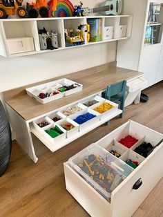 two bins filled with legos on top of a wooden floor next to a white desk