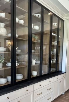 a cabinet with glass doors and white dishes on it