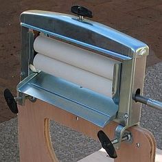 a machine that is sitting on top of a wooden stand with rolls of paper attached to it