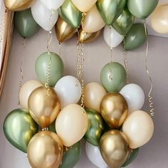 many balloons are hanging from the ceiling with gold, green and white balls attached to them