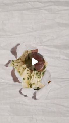 a piece of food sitting on top of a white tablecloth covered in wax paper